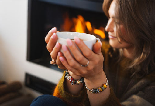A cozy moment in front of the fireplace while drinking a cup of tea and wearing Trollbeads autumn jewellery