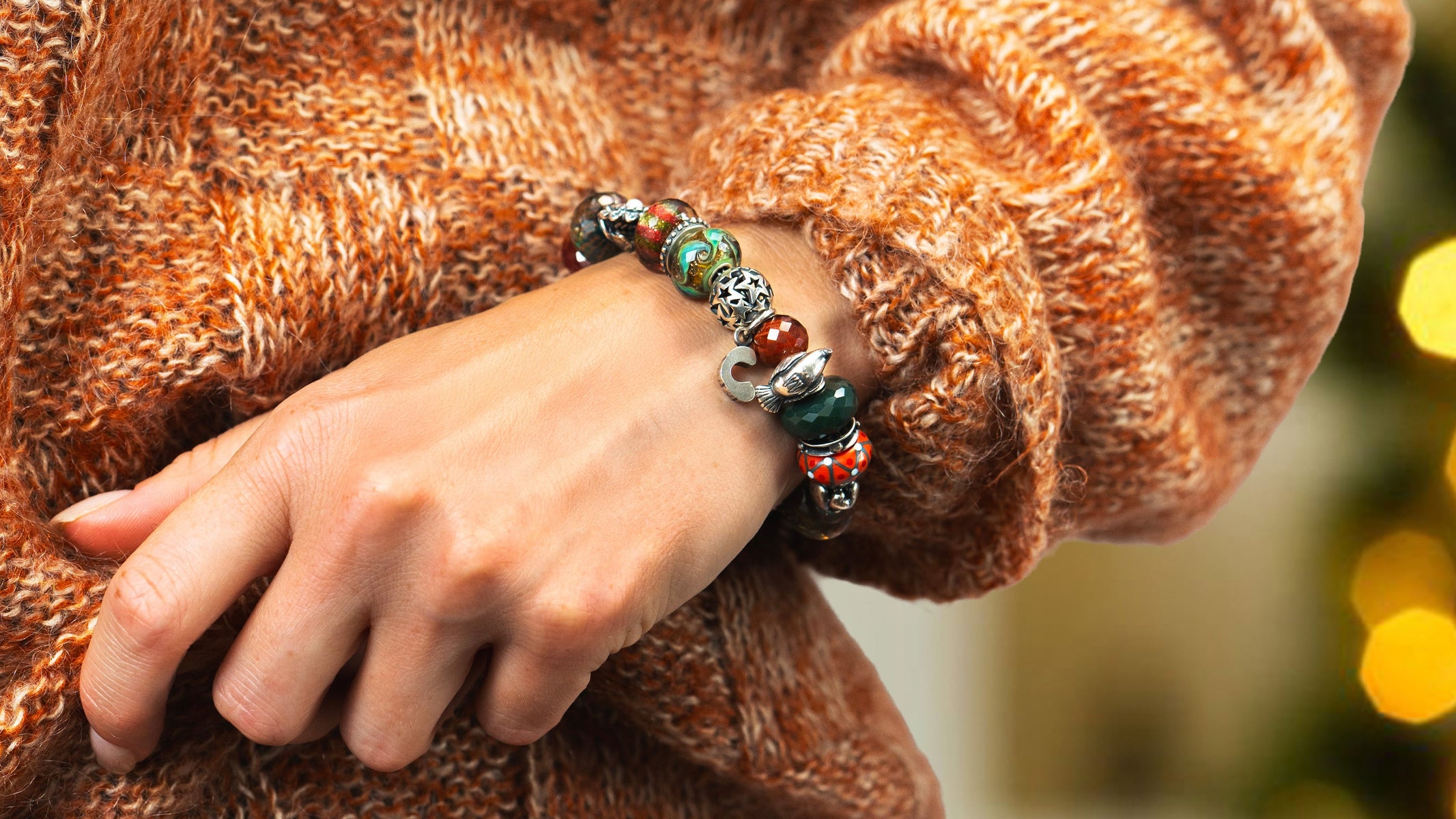 Model wearing a sweater and a christmassy bracelet with shimmering beads in glass and silver