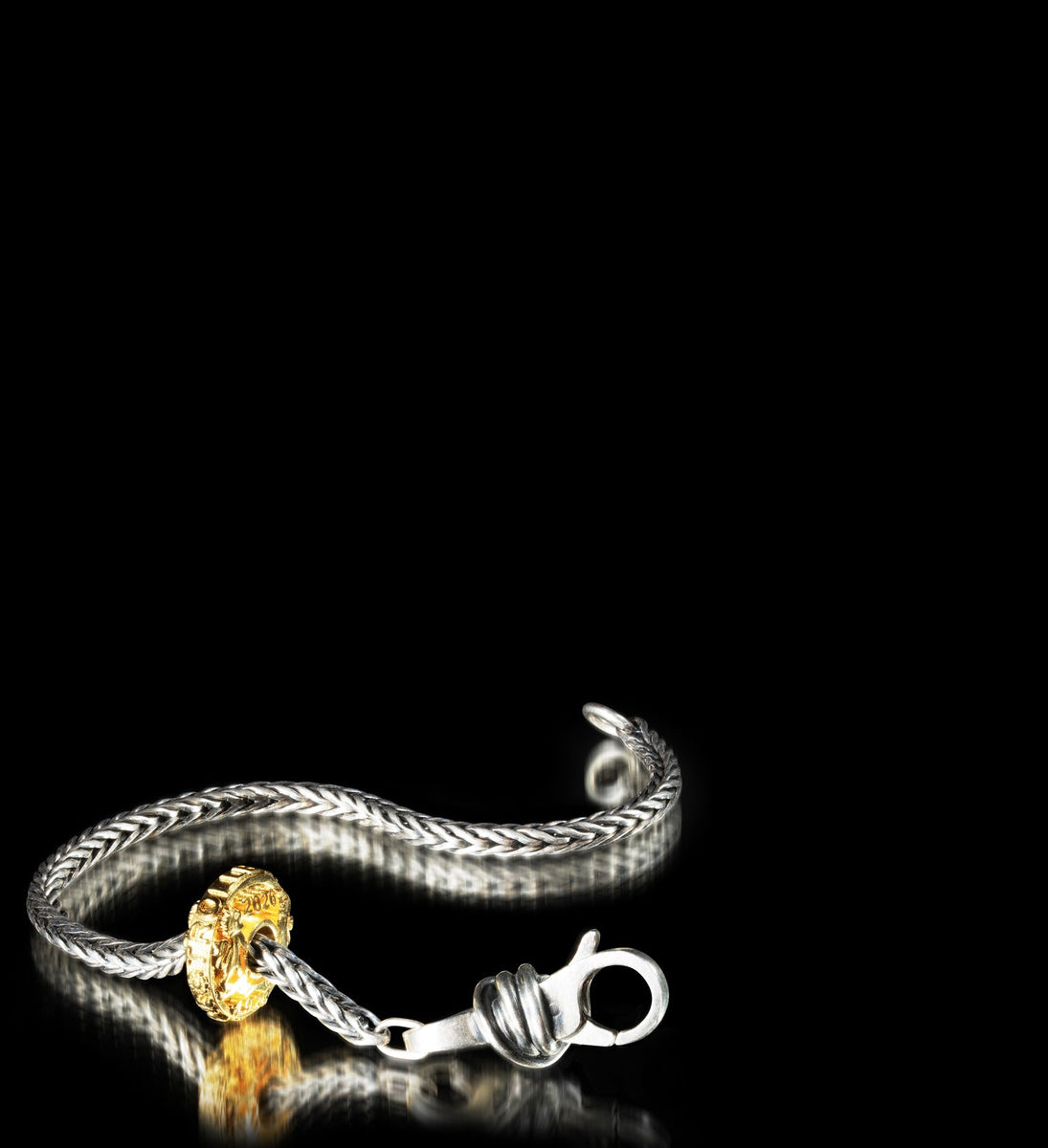 Silver bracelet with a gold-plated bead on a black background