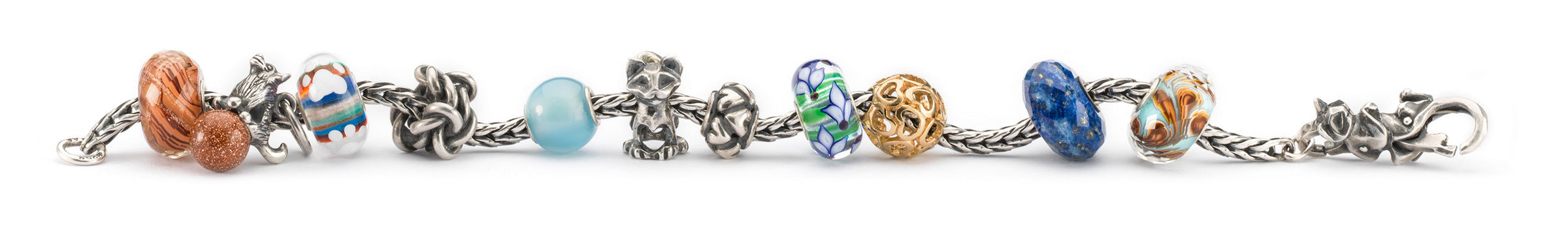 Trollbeads bracelet a mix og beads in gold, silver and gemstones, one glass bead with a small paw print charm, and beads with cats and a dog representing the cherished bond and affection between pets and their owners.
