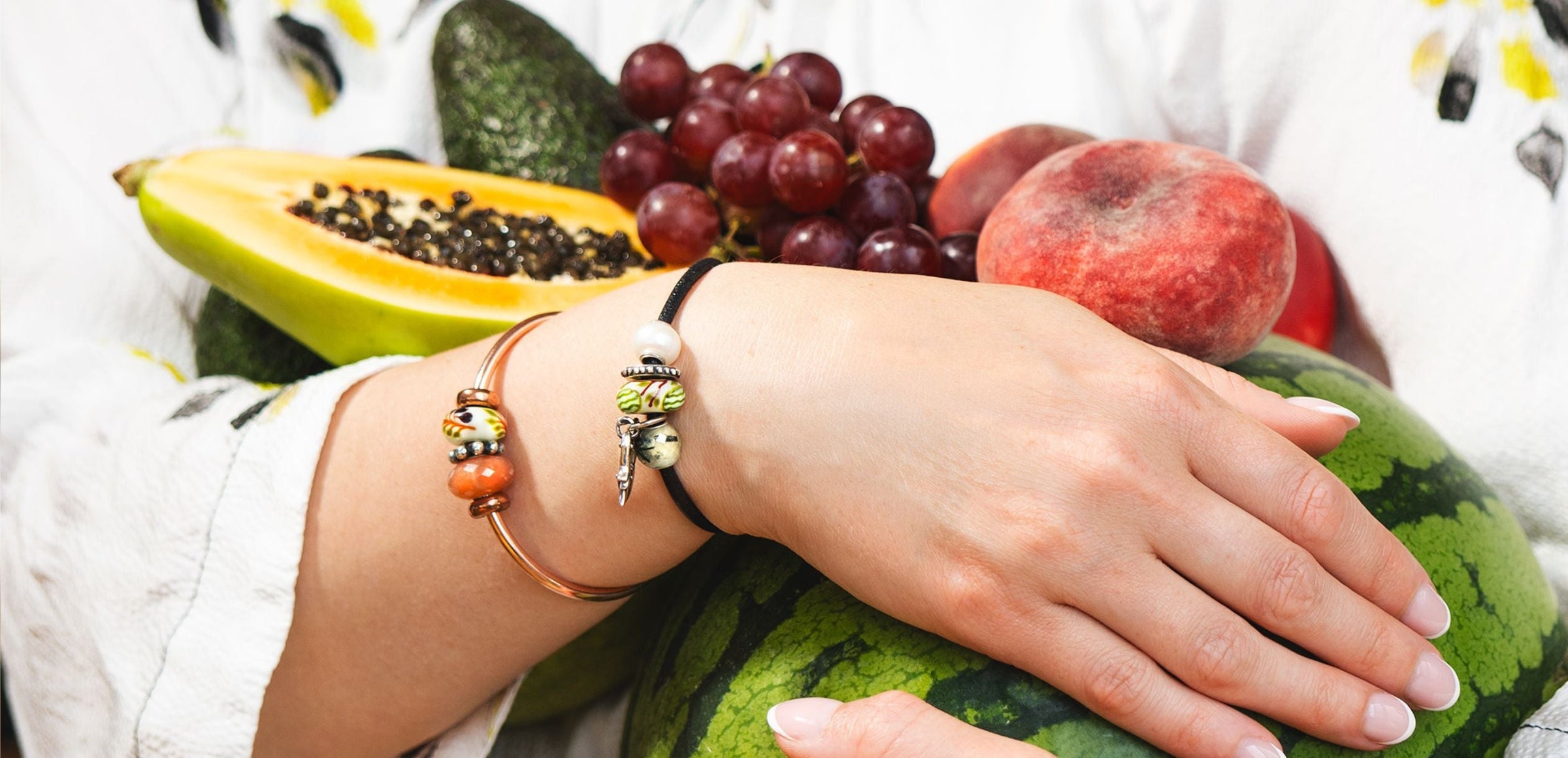 Model holding various fruit while wearing bracelets with beads
